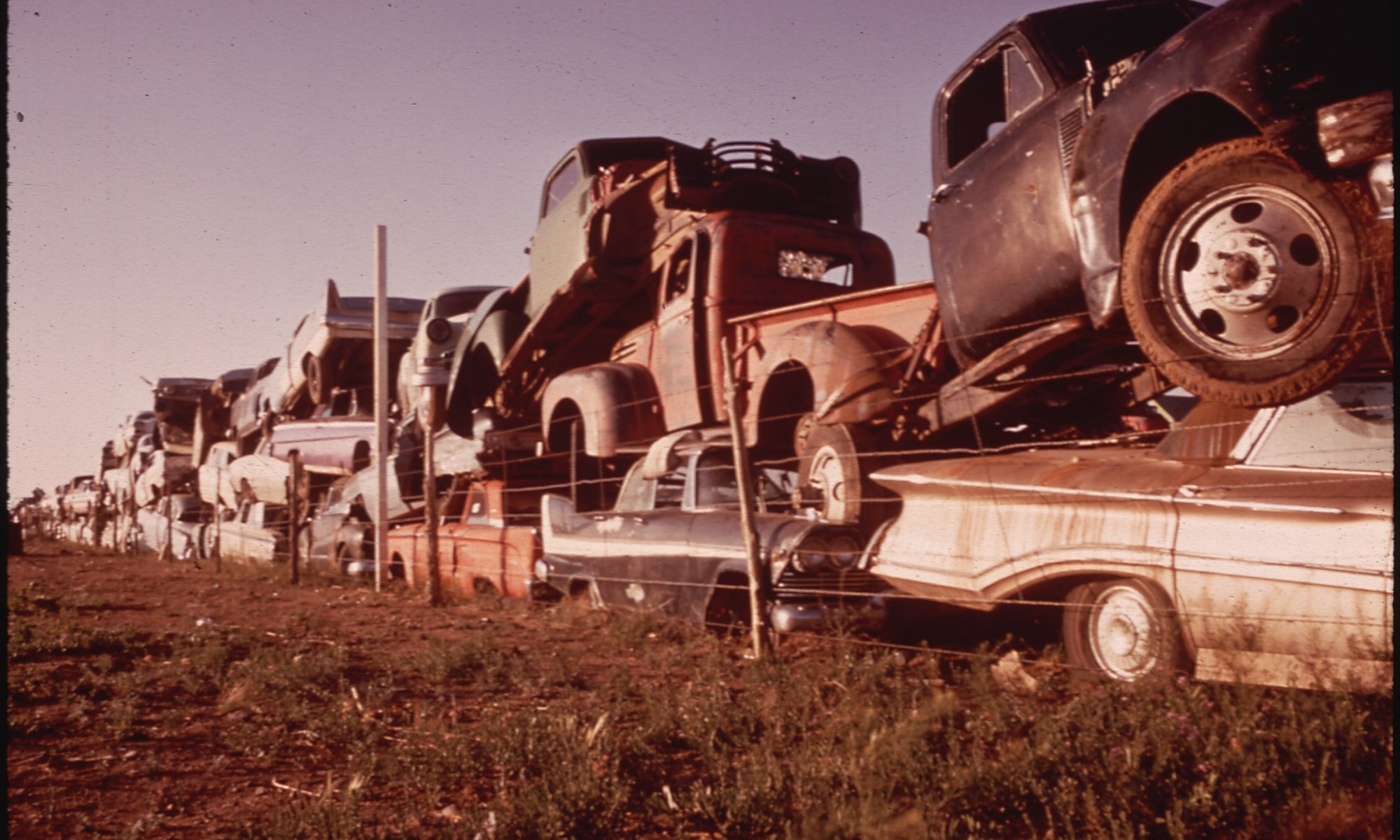 Junked Automobiles Are Piled Three Deep Along Fence